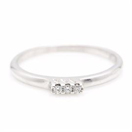 18K White Gold Diamond Ring: An 18K white gold ring featuring three diamond center stones held in a raised prong setting stylistically tilted to one side.