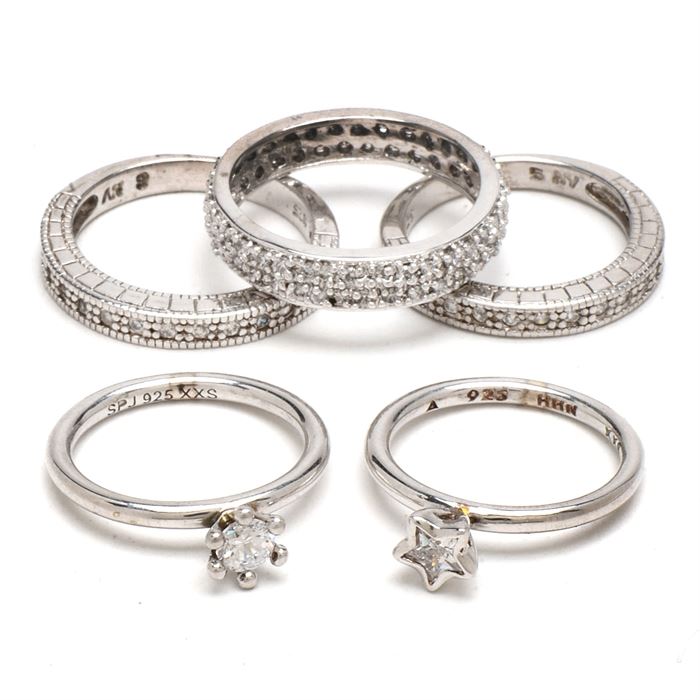 Sterling and Cubic Zirconia Rings: A selection of five sterling silver rings set with cubic zirconia. The rings have a variety of styles, including a solitaire stone in the shape of a heart, channel-set and pavé designs. The total weight, inclusive of all materials, is 0.375 ozt.