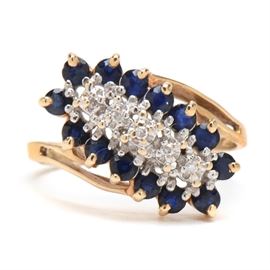 10K Yellow Gold Diamond and Red Sapphire Ring: A 10K yellow gold diamond and sapphire ring. This ring features a row of diamonds surrounded by natural blue sapphires with beaded accents.