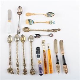 Flatware Including Silver Plate: An assortment of flatware. It includes five iced tea spoons with various finials at the ends including a shield and fleur-de-lis; a gold tone fork and spoon set depicting Moscow; a Georgia souvenir spoon; two knives with plastic marbleized handles; and more.
