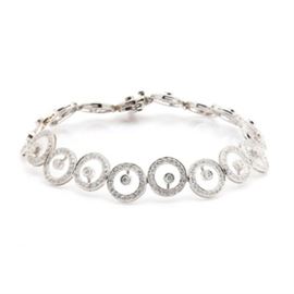 18K White Gold 2.25 CTW Diamond Bracelet: An 18K white gold 2.25 ctw diamond bracelet. This bracelet showcases three hundred and seventy-eight round brilliant cut diamonds adorned throughout the concentric design. This piece features a decorative hidden box tab clasp with a safety catch.
