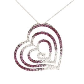 18K White Gold Pink Sapphire, Ruby and Diamond Pendant With 14K White Gold Chain: An 18K white gold pink sapphire, ruby and 0.97 ctw diamond pendant with a 14K white gold chain necklace. This pendant features an openwork heart motif, which graduates down in size to the center and steps down in depth. The gemstones also graduate in color from diamonds to variegated colors of pink sapphires and rubies. A 14K white gold chain necklace is included.