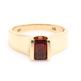 10K Yellow Gold Garnet Ring: A 10K yellow gold and garnet ring. This ring features highly polished flared shoulders leading to a bezel set garnet.