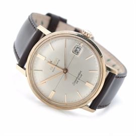 Omega Seamaster Stainless Steel Automatic Wristwatch: An Omega Seamaster stainless steel wristwatch with a brown leather band leading to a circular gold tone bezel. The bezel houses a champagne colored dial with gold tone hour indicators and hands, as well as a magnified date window at the 3 o’clock position.