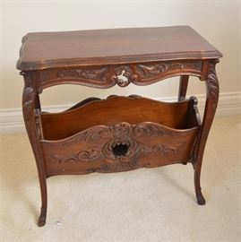 Victorian Style End Table: A Victorian style end table. This table features a molded edge top above a carved serpentine shaped apron that rises above cabriole legs. The legs are connected by a carved stretcher that features a pair of compartments.