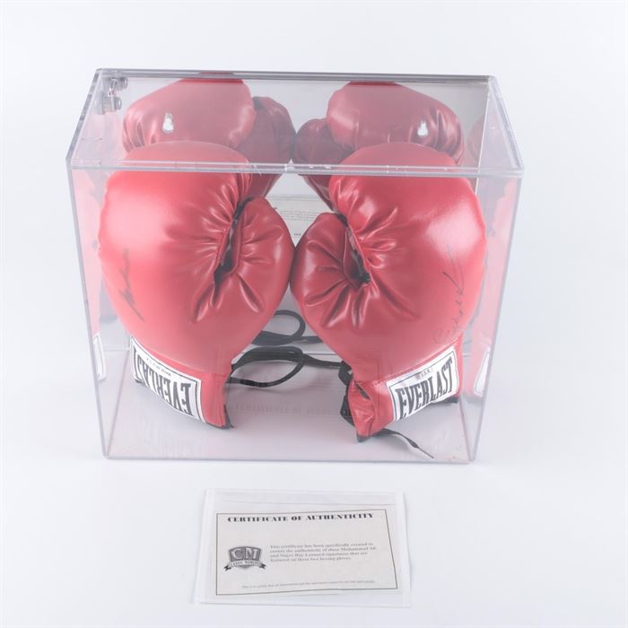 Muhammad Ali and Sugar Ray Leonard Signed Boxing Gloves: A pair of signed boxing gloves from Muhammad Ali and Sugar Ray Leonard. These red-tone Everlast brand gloves are marked to the sides in black-tone permanent ink signatures, and housed in a hard plastic display case. The plastic case locks and comes with a key. The gloves come with a certificate of authenticity from Classic Moments.