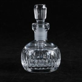 Waterford Cut Crystal Decanter: A small decanter by Waterford. This short crystal piece features a fluted pattern of cuts to the stopper and the small round body of the decanter. The piece is etched to the base “Waterford”.