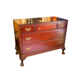 Chippendale Style Mahogany Chest Of Drawers With Glass Top: A Chippendale style mahogany chest of drawers with a glass top. The chest of drawers features a rectangular top with a fitted piece of glass, quarter length drawers to either side of a half-length drawer over two full length drawers, and cabriole style legs with claw and ball feet on the front and back sides. The center drawer has a pair of small round glass knobs, the others have bail pulls with willow style backplates. Carved acanthus and vertical fluted detail on the front corner edges further enhance the piece. The drawers are held together with dovetail joinery.