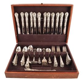 Wallace "Old Atlanta" Sterling Silver Flatware Set: A 70-piece Wallace sterling silver flatware set in the Old Atlanta pattern. This discontinued ornate pattern introduced in 1960 has an embossed curved design to the handle. The pieces include twelve dinner knives with stainless steel blades, twelve dinner forks, twelve salad/dessert forks, twenty-four teaspoons, two soup spoons, four serving spoons, one meat fork, one ladle, one sugar spoon, and a flat handle butter knife. The pieces come in a wooden felt lined silver chest by Pogue’s Cincinnati. The combined weight of all of the pieces is approximately 66.45 ozt. The weight does not include the pieces with stainless steel blades.