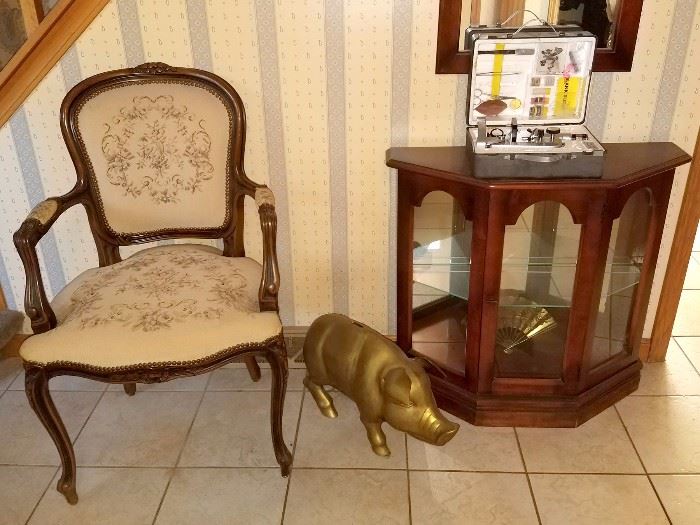 Accent chair. Brass piggy bank. Curio cabinet