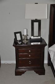  One of the two cherry wood two drawer nightstands from Macy's available 27.5"w x 27" h x 17" d. Shown with Jerry Antique Silver table lamp (2 available) for Robert Abbey inc.