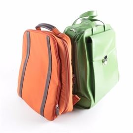 Assortment of Computer Bags: A pair of computer bags made by Jack Georges and Levenger. The Green leather Jack Georges bag features wheels and a retractable handle for portability, as well as a padded interior to protect items inside. The Orange nylon Levenger backpack includes removable shoulder straps as well as a padded interior.