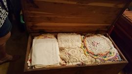 Antique cedar chest with wheels.  Tons of hand made table runners, doilies am more! 