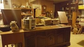 Antique record player in beautiful credenza.  Bunch of old vinyl records, various sizes and artists. 
