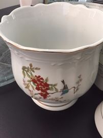 White pot with red flower and upside down blue bird. Why is the bird upside down. Was it supposed to be a light fixture and now we are trying to sell it as a pot? Mystery