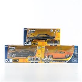 Jada Dub City Bigtime Muscle Die-Cast Cars: A group of three Jada Dub City Bigtime Muscle 1:24 scale die cast cars. This selection includes a 1967 Chevy Nova SS in black and two 1969 Pontiac GTO Judges in black and orange. Each is contained in its original packaging.