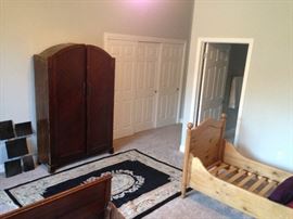 Art Deco-era armoire with rug and two wooden bed frames. Staging furniture and antique.