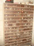 Large porcelain knobbed wooden cabinet organizer with everything from drill bits, to ???? all drawers are full. Cabinet stands over 6' tall.