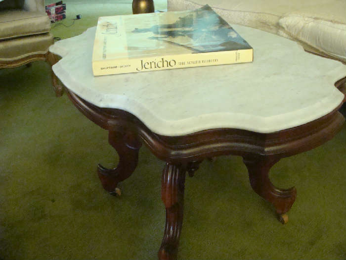 Antique marble top scalloped edge table with wooden casters in lovely condition.