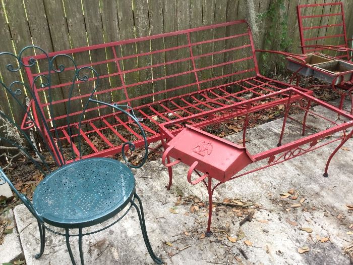 Vintage red metal patio sofa, coffee table, side table, green ornate chair.