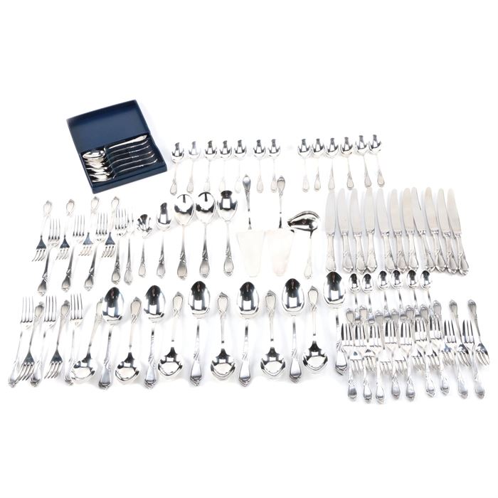 Hefra "Rhapsody" 800 Silver Flatware Set: A 800 silver flatware set by Hefra S.A. of Warsaw, Poland. This set is in the Rhapsody pattern, which features an Art Nouveau-inspired plant motif to the handle. This eighty-eight piece set includes eighteen cake forks, thirteen dinner forks, eleven dinner knives, twelve soup spoons, three serving spoons, two cake servers, a sugar spoon, a gravy ladle, a place spoon, a pickle fork, nineteen teaspoons, and six salt spoons. Each is marked to the back with a “W” assay for Warsaw next to a right facing woman’s head and “3” for 800 silver, the Hefra maker’s mark, and “800”. The total approximate weight, excluding dinner knives with stainless steel blades, is 107.905 ozt.