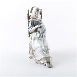 A Lladro "Embroidery Lady" Figurine: A vintage Lladró “Bordadora Insular” porcelain figurine, also known as the “Embroidery Lady”. The figurine depicts a woman doing needle work; she is seated in a ring turned, ladder back chair and wears an apron with a handpainted pattern. Marked “Lladró / Made in Spain” to the bottom with maker’s mark.