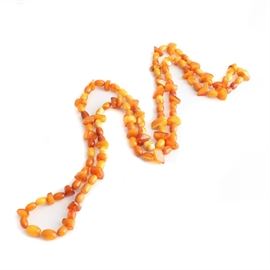 Rope Length Amber Necklace: A rope length amber necklace. This necklace features a continuous strand of oval and tumbled free-form beads of mutton fat and caramel colored amber.