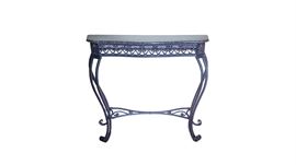 Black Marble Top Metal Console Table: A black marble top metal console table. This piece features a black marble top with white and orange veining and a black metal base. The top rests above an open work apron with foliate corner blocks to the front. The table rises on cabriole style legs ending in scroll feet, with a scroll accented center stretcher. The table is unmarked.
