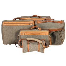 Set of Vintage Hartmann Luggage: A set of vintage Hartmann luggage. The set includes five pieces; two suitcases on rollers, a rolling carry on bag, a duffel bag and a garment bag. The cases are made of brown tweed with brown leather accents marked “Hartmann”. One leather flap is stamped in red “April 6, 1998”.