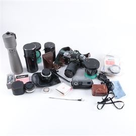 Vintage Minolta XE-5 and 16 EE II Cameras with Accessories: A pair of vintage Minolta cameras with accessories. The pair includes a Minolta XE-5 35mm SLR camera and a Minolta 16 EE II 16mm subminiature camera. The XE-5 features an attached lens and strap, and the 16 EE II features a slim silver-tone design and a black leather case. The cameras include additional lenses from Minolta, a Tele-Bewi rangefinder, a Weston light and exposure meter, filters, informational paperwork, and more.