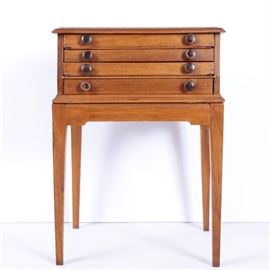 Antique Spool Cabinet: An antique spool cabinet. It has four shallow drawers stacked in a top portion with rounded edges, set on a rectangular table base with plain apron and tapered block legs. Each drawer has two wooden knobs.