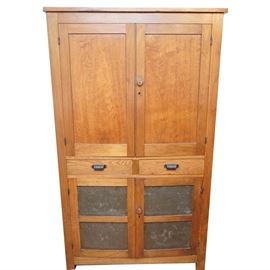 Vintage Pine Pie Safe: A vintage pine pie safe featuring two hinged, panel cabinet doors that open to two fixed shelves and a vertical plank back. There is one wood knob, a key eschuchon, and a pivoting wood stay on the other door’s interior. The bottom case features two dovetail constructed drawers with decorative metal pulls and two hinged cabinet doors with pierced tin. The tin pattern is a star inside a circle with a smaller stars in the corners. The bottom cabinet contains a single shelf.