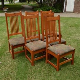 Mission Style Dining Chairs by Arhaus: A set of six matching Mission style dining chairs by Arhaus Furniture. They each have a slatted back set under a concave curved top rail, between block stiles that extend down to the back legs. These connect to the front block legs by an offset box stretcher, and have convex curved aprons to echo the top rail. The square seats are padded and upholstered in a floral tapestry-like fabric. The maker’s tag can be found on the underside.