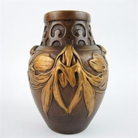 Art Nouveau Inspired Vase by H.L. Desrousseaux: An art nouveau inspired enameled ceramic bulb-shaped vase after Henri Laurent Desrousseaux (1862 – 1906). The piece features a painted finish in warm shades of bronze and gold, and is decorated in light relief with graceful, voluminous floral swags. It is signed in cursive “H.L. Desrousseaux” on the side, and stamped “Ceramique D’Art 69” on the bottom.