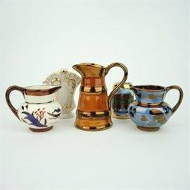 Vintage Lusterware Cream Pitchers: A selection of vintage lusterware pitchers and more. The pieces include three lusterware collectibles, all of which are notably marked . A petite bone china vase and miniature porcelain “Heidelberg” tankard complete the grouping.