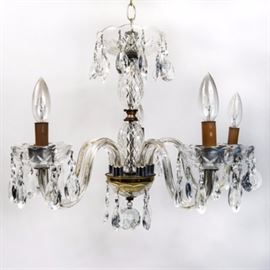 Vintage Crystal Chandelier: A vintage crystal chandelier with hanging tear-drop prisms. The lamp features five scrolling candlestick arms and cut crystal bobeche bowls hung with tear drop prisms. The center post has faceted crystal and well, and is finished with a brass cap and hanging spherical finial. Arms can be adjusted in their position.