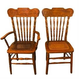 Set of Vintage Caned Seat Dining Chairs: A set of four vintage caned seat dining chairs. The set includes a pair of armchairs and a pair of side chairs. These chairs feature a carved crest rail above a turned spindle back attached to the square seat with inset cane that rises above turned legs connected by a turned double box stretcher.