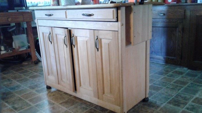 WOODEN KITCHEN ISLAND.  PLENTY OF STORAGE FOR YOUR COOKING NEEDS AND IS EASILY MOVED BECAUSE IT IS ON WHEELS!