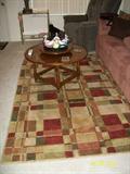 Rug and round wood coffee table with lazy susan in center.