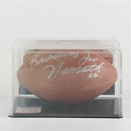 Joe Namath Signed Football: A Joe Namath signed football. This football features the signature of former quarterback and football Hall of Famer “Broadway” Joe Namath in silver tone ink. The ball is presented in a clear protective case with black base and includes a certificate of authenticity from “PSA/DNA” numbered “I 75880”.