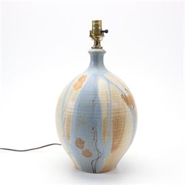 Hand Thrown Wishon-Harrell Stoneware Table Lamp: A beautifully made Wishon-Harrell stoneware table lamps. This selection includes a single socket, urn-shaped table lamp with a light blue, cream, brown, and off white color palette, and a floral motif throughout. Wishon Harrell pottery was founded by Jim Wishon and Jerry Harrell, who each had a role in the creation of their work. They founded their studio and worked in both Muncie, Indiana and San Diego, California in the 1990s. Jim Wishon threw the work on the wheel and Jerry Harrell glazed and decorated the pieces. Harrell died in the 1990’s, ending their artistic collaboration.