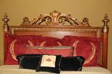 CLOSEUP VIEW OF HIGHLY CARVED AND DECORATIVE HEADBOARD.
