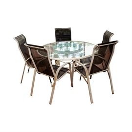 Round Patio Table and Five Chairs: A round patio table and five chairs. This round white metal framed patio table features a two tiered glass top with etched floral motif and curved legs and comes with five brown mesh high-back chairs with white metal curved frames, open sides an curved legs.