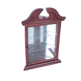 Federal Style Cherry Wall Mounted Corner Curio Cabinet: A Federal style cherry wall mounted corner curio cabinet. This wall cabinet features a broken scroll pediment and triangular top over a cabinet door with a glass pane that opens to two glass shelves and mirrored back. The cabinet sits on a moulded base. The back is marked with a sticker.