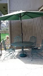 Green wrought iron patio table with four spring action chairs, large umbrella and base