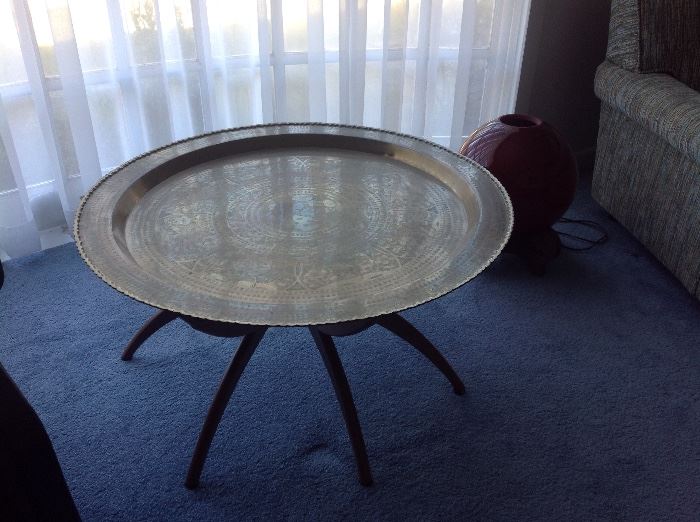 Brass table with spider legs from the 1960's.   There is a red decorative light sitting to the right of the table.  Both items were brought from Japan.