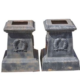 Pair of Cast Iron Pillars: A pair of cast iron pillars. This pair of cast iron pillars both features square openings to the tops, flared rims with gadroon motif, square bodies with raised garland accents on each side and flared bases with repeating gadroon accents and opening at the bottom.