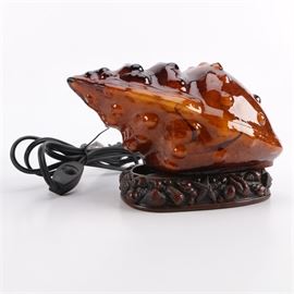 Shell Shaped Glass Accent Lamp: A glass accent lamp. This features an amber colored glass shade in the form of a sea shell with one light socket on a wooden base with shell motif.