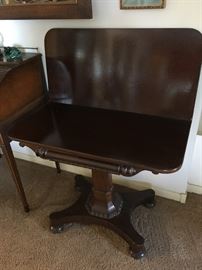 An Empire mahogany swivel game/ card table with storage underneath.