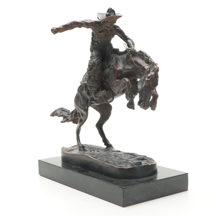 Brass Sculpture After Frederic Remington's "Bronco Buster": A bronze sculpture after the sculpture by Frederic Remington (1861-1909), the very popular American West artist of the 19th century. This striking piece, titled Bronco Buster, depicts a wild horse trying to throw his rider while the hardened cowboy stays in the saddle to break this bucking bronco. The base is engraved with a reproduction signature. Back of horse is branded with a triangle in a circle brand. The sculpture has been mounted onto a marble base.